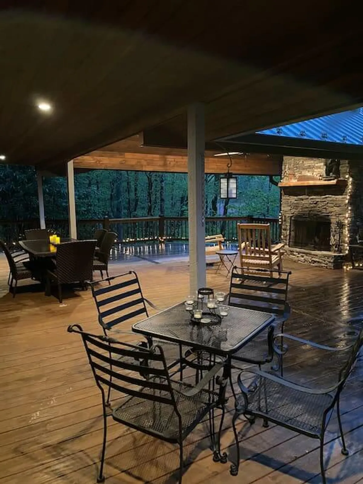 An inviting outdoor scene featuring a stone fireplace, dining table, and comfortable seating surrounded by trees, creating a cozy yet upscale retreat. The ambiance is tranquil and ideal for socializing or relaxing after a round of golf.
